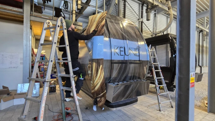 Fachgerechte Montage einer Teil- oder Vollfolierung an einer Seilbahngondel in Tirol. Das Motiv wird präzise angepasst und blasenfrei verklebt – für eine langlebige und professionelle Gondelbeklebung.