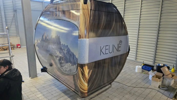Seitliche Teilbeklebung einer Seilbahngondel mit integriertem Markenlogo. Diese Form der Gondelfolierung bietet starke Sichtbarkeit bei reduzierter Flächenabdeckung.